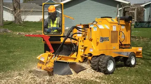 A tree expert working with a stump grinder in a stump grinding project